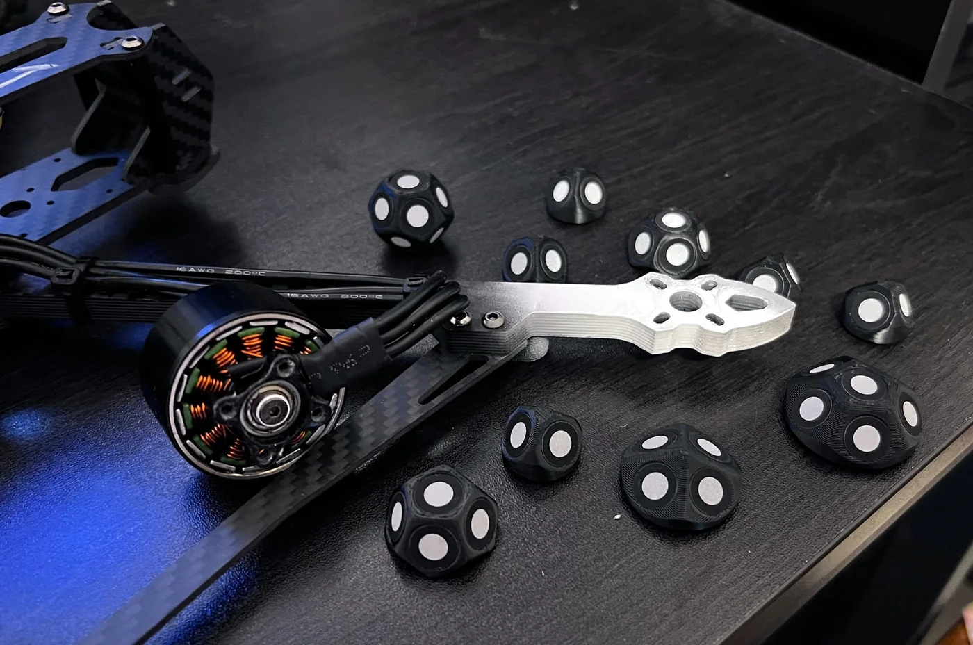 A drone arm on a desk, among white-dot markers.